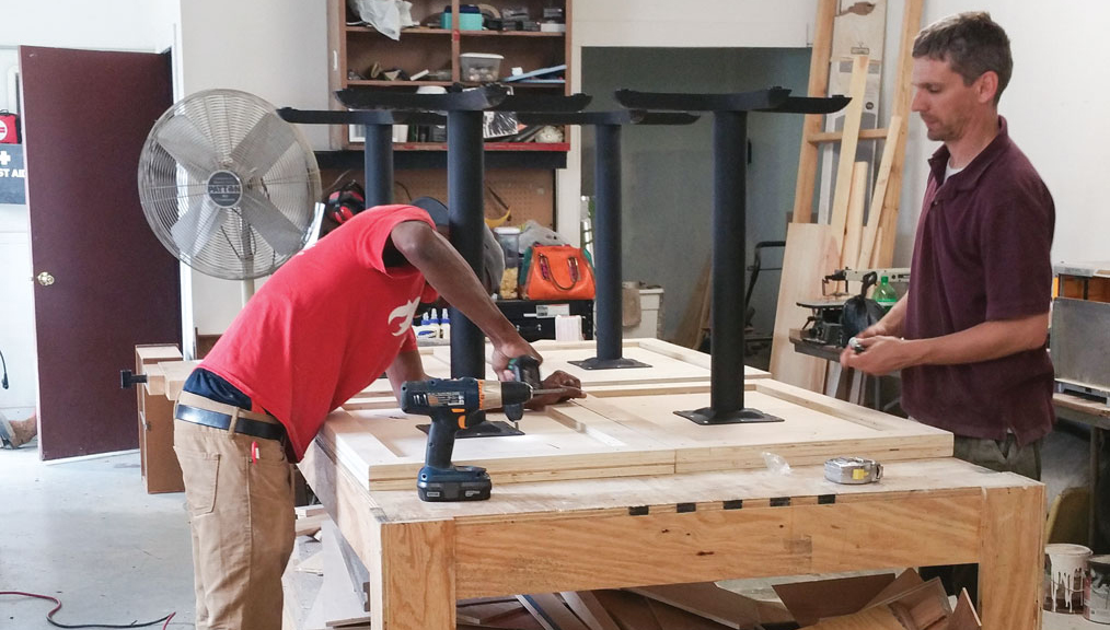 Workers construct café tables from reclaimed materials at L!VE Café in Chicago, Illinois.